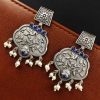 A close-up view of silver floral art earrings dangling elegantly.