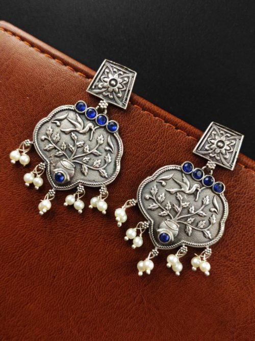 A close-up view of silver floral art earrings dangling elegantly.