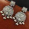 A close-up view of silver floral art earrings dangling elegantly.