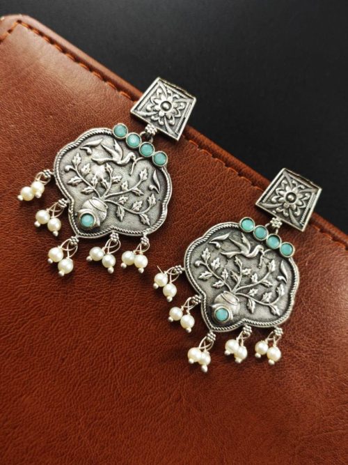 A close-up view of silver floral art earrings dangling elegantly.
