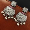 A close-up view of silver floral art earrings dangling elegantly.