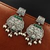 A close-up view of silver floral art earrings dangling elegantly.
