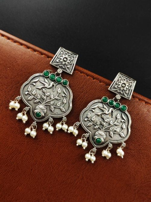 A close-up view of silver floral art earrings dangling elegantly.