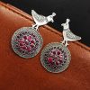 Silver Replica Peacock Earrings resting on a black velvet background