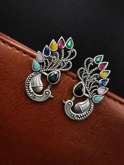 Peacock Stud Earrings displayed against a rustic backdrop.