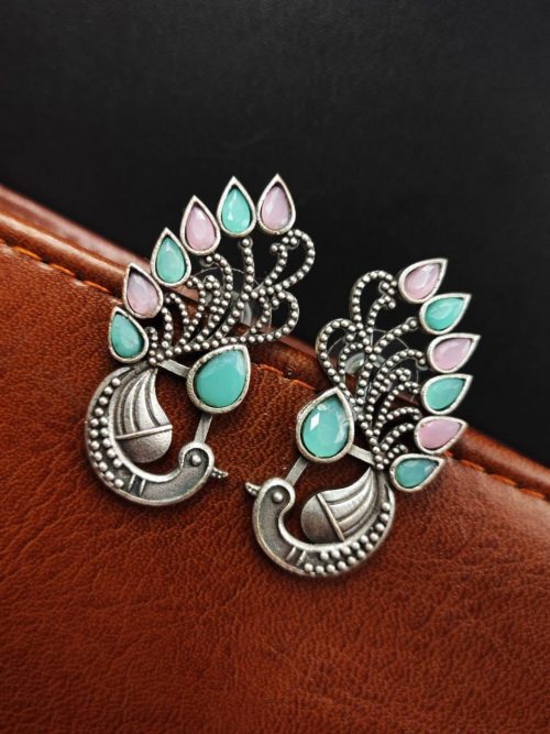Peacock Stud Earrings displayed against a rustic backdrop.