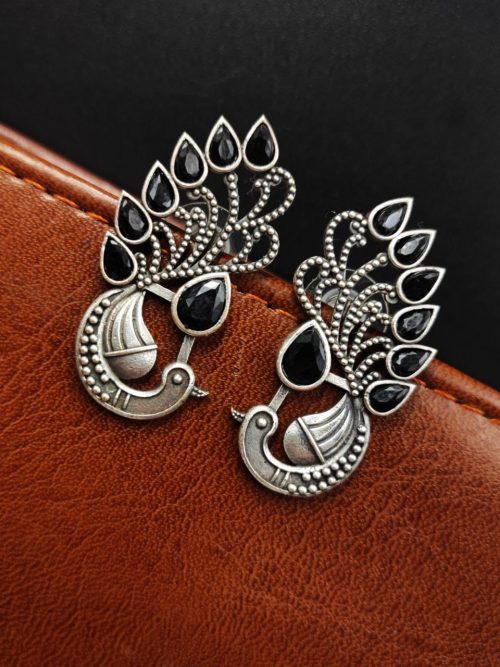 Peacock Stud Earrings displayed against a rustic backdrop.