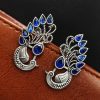Peacock Stud Earrings displayed against a rustic backdrop.