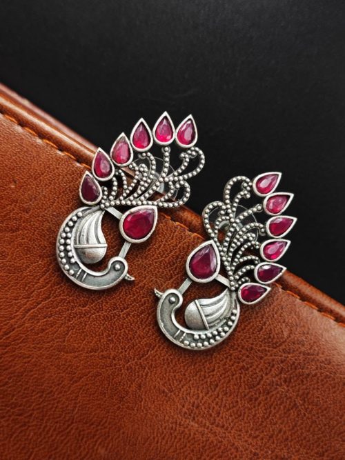 Peacock Stud Earrings displayed against a rustic backdrop.