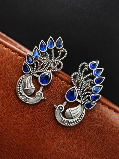 Peacock Stud Earrings displayed against a rustic backdrop.