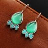 Silver Replica Stone Earrings with oxidized hooks displayed against a textured background