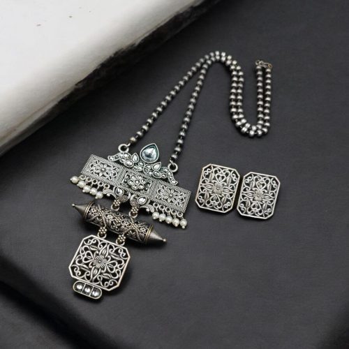Silver look necklace set with a unique oxidized pendant and matching earrings featuring intricate detailing.