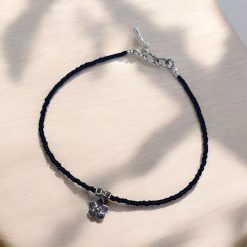 Silver flower charm anklet with black glass beads and flower charm, offering an elegant and stylish look