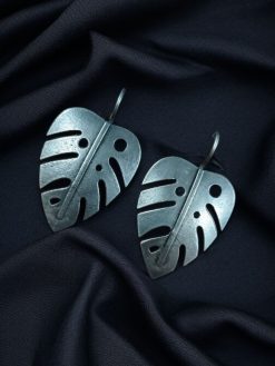 Oxidized monstera leaf earrings with a silver replica finish and hook closure, inspired by nature.