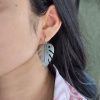 Oxidized monstera leaf earrings with a silver replica finish and hook closure, inspired by nature.