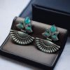 Handcrafted oxidized silver-plated peacock dangler earrings with stone detailing and pearl accents.