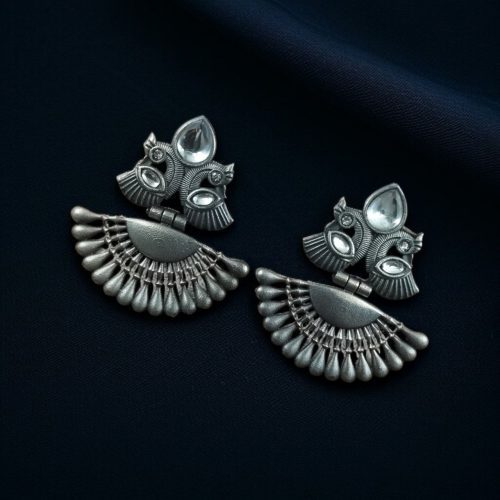 Handcrafted oxidized silver-plated peacock dangler earrings with stone detailing and pearl accents.