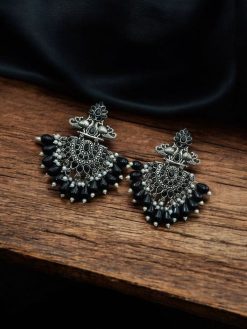 Close-up of silver-plated brass peacock earrings adorned with sparkling stones, featuring intricate ethnic detailing
