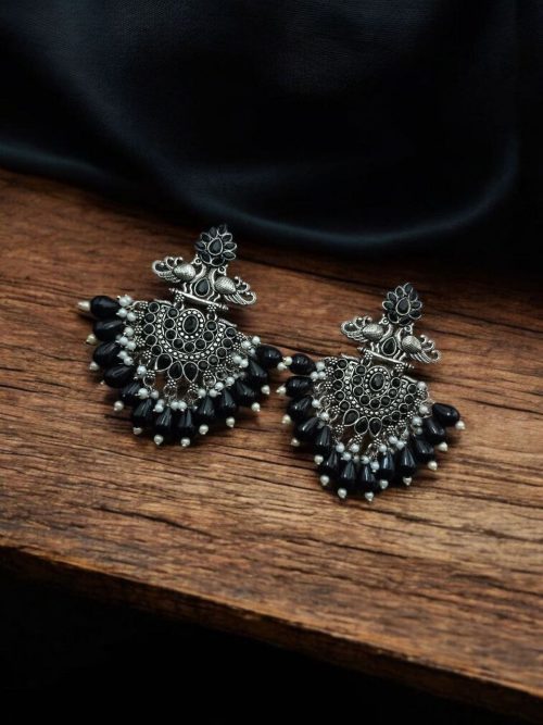 Close-up of silver-plated brass peacock earrings adorned with sparkling stones, featuring intricate ethnic detailing