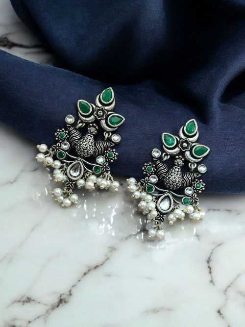 Close-up of handcrafted brass bird stud earrings with embedded beautiful stones, nature-inspired jewelry design