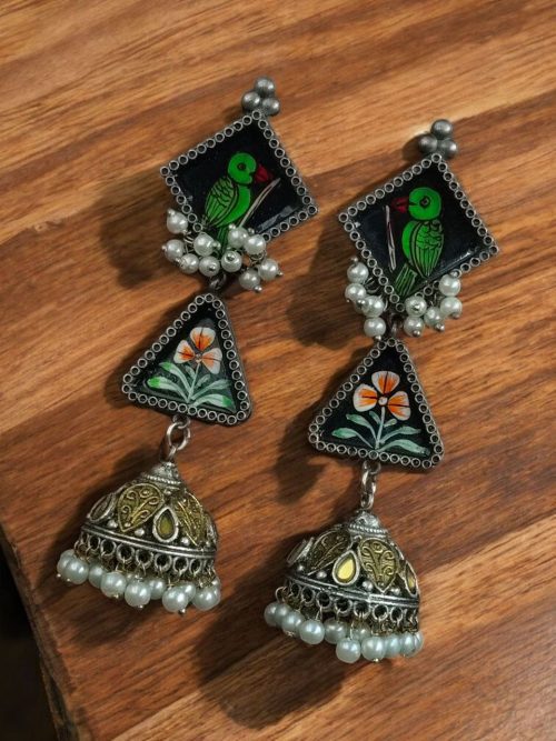 Handpainted two-tone German silver jhumka earrings with parrot stud, ethnic design, lightweight and perfect for festive wear.