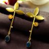 Premium gold-plated brass long stud earrings featuring sparkling Monalisa stones, perfect contemporary design.