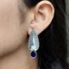 Traditional oxidized silver stud earrings with floral art, pearl, and stone work.