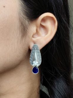 Traditional oxidized silver stud earrings with floral art, pearl, and stone work.
