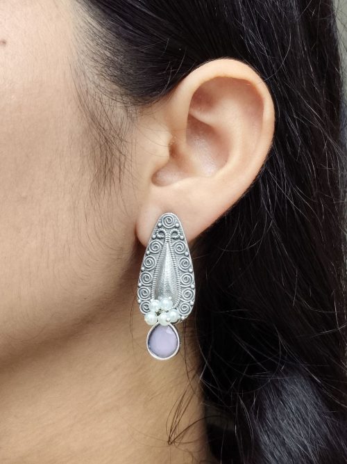 Traditional oxidized silver stud earrings with floral art, pearl, and stone work.