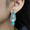 Traditional oxidized stud earrings with floral art, pearl, and stone work.