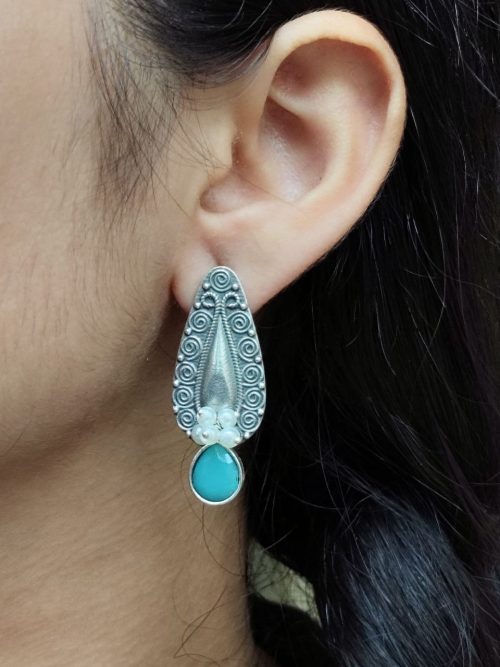 Traditional oxidized stud earrings with floral art, pearl, and stone work.
