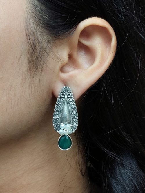 Traditional oxidized silver stud earrings with floral art, pearl, and stone work.
