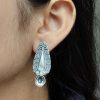 Traditional oxidized silver stud earrings with floral art, pearl, and stone work.