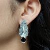 Traditional oxidized silver stud earrings with floral art, pearl, and stone work.