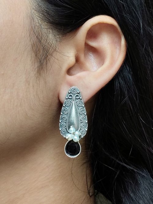 Traditional oxidized silver stud earrings with floral art, pearl, and stone work.