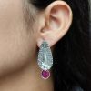 Traditional oxidized silver stud earrings with floral art, pearl, and stone work.