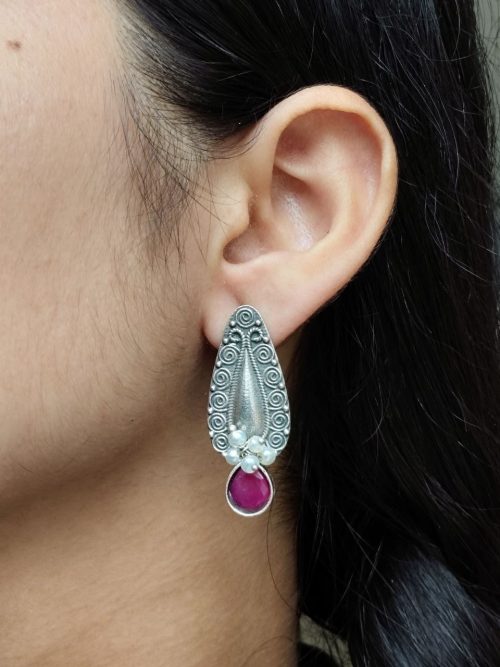Traditional oxidized silver stud earrings with floral art, pearl, and stone work.