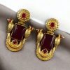 Traditional gold plated earrings with bird design and green stones in vintage style.