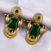 Traditional gold plated earrings with bird design and green stones in vintage style.