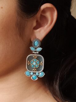 Two-tone oxidized dangler earrings with Monalisa stone and silver replica finish.